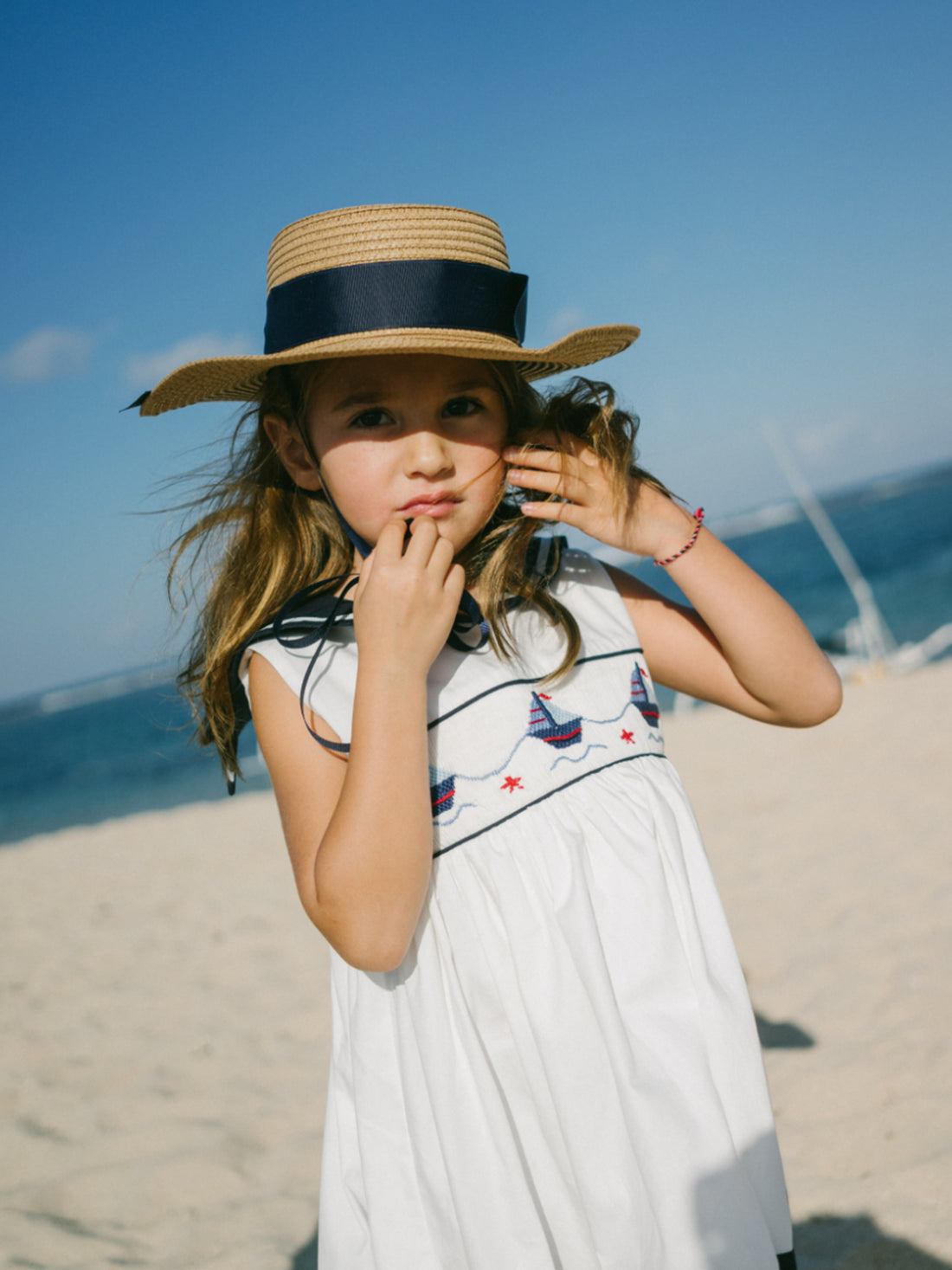girl wearing french style sleeveless beach dress with toy boat handmade smock